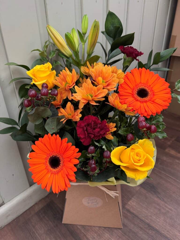Autumn flower box with orange gerberas, yellow roses, orange chrysanthemums and lilies